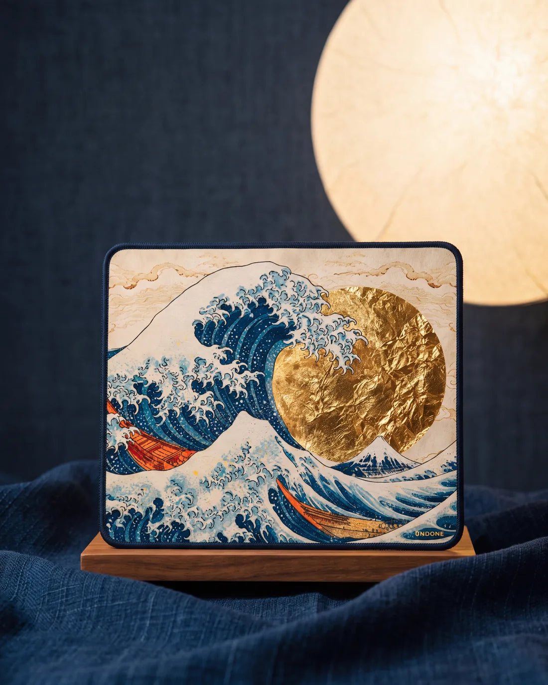 The Hokusai Watch Cloth on a wooden stand, printed with the Great Wave and a gold-leaf sun