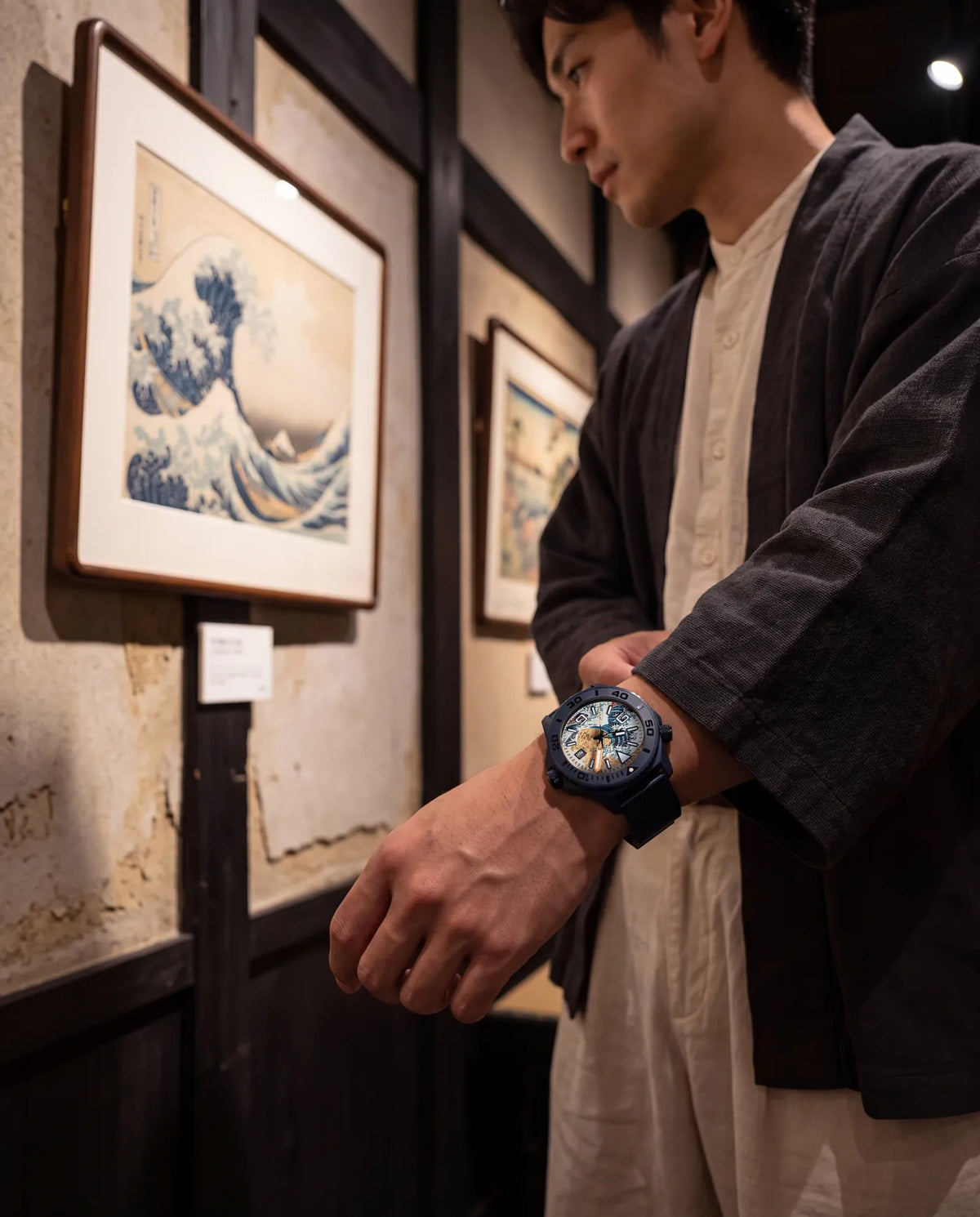 Arms folded in front of a framed Great Wave print